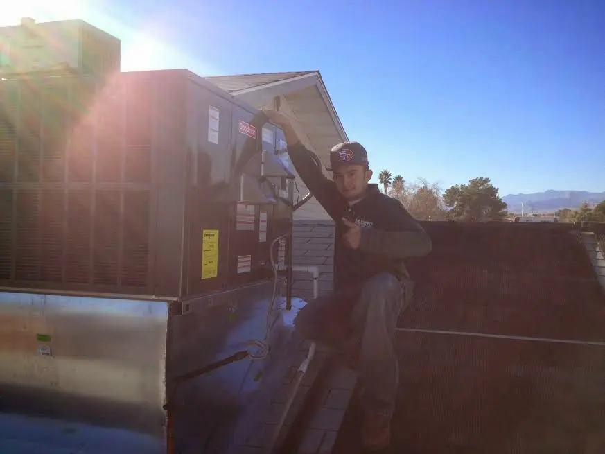 HVAC technician performing AC Tune-Up on a rooftop unit in Bethel